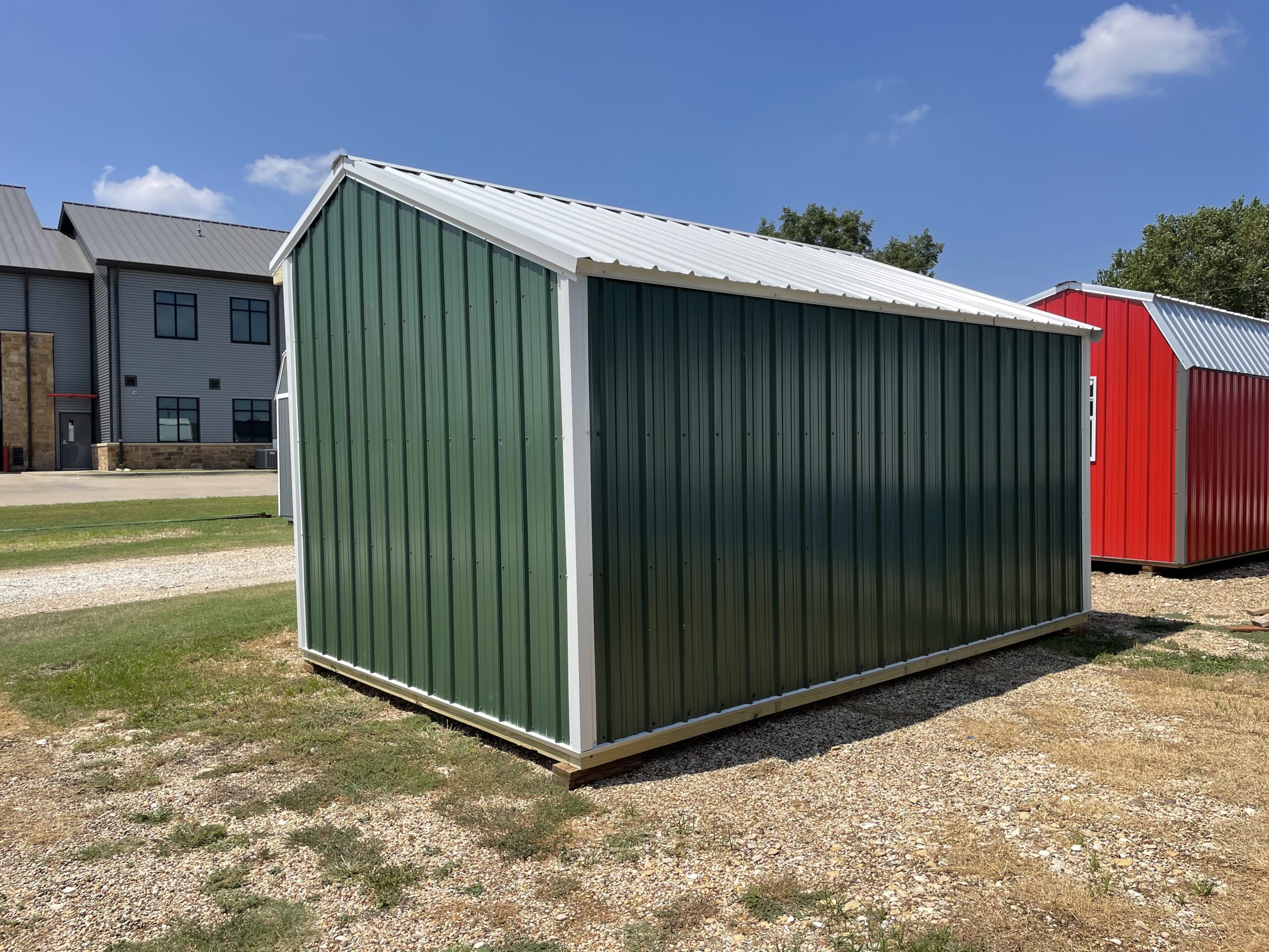 back of loafing shed with evergreen metal siding, white trim and white roof 